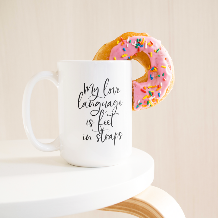 Love_Language_Is_Feet_Straps_Mug_15ozWhiteMugLifetsyleDonutLH_Mockup.png