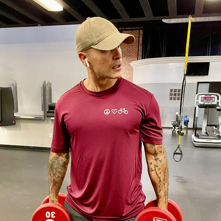 Man wearing a red moisture wick t-shirt that says peace, love, biking