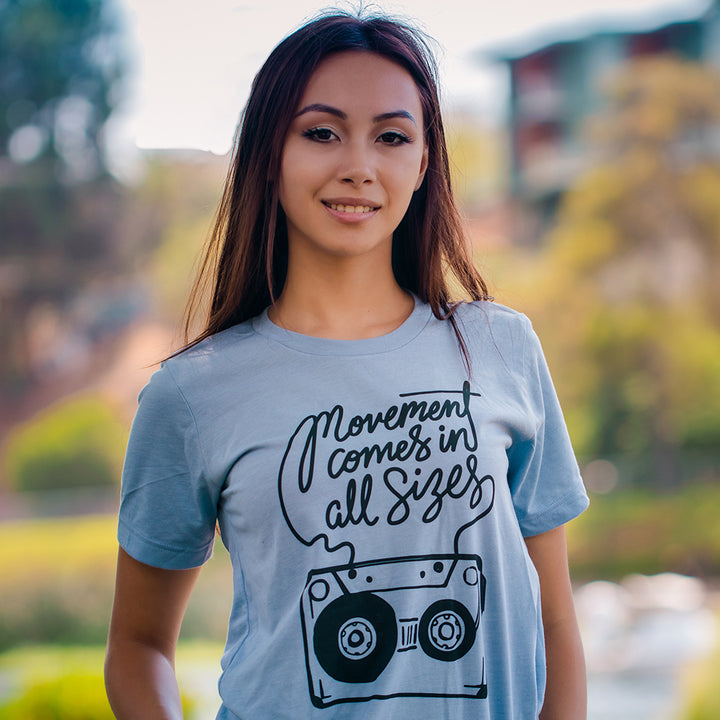 Woman wearing a blue t-shirt that says "movement comes in all sizes"