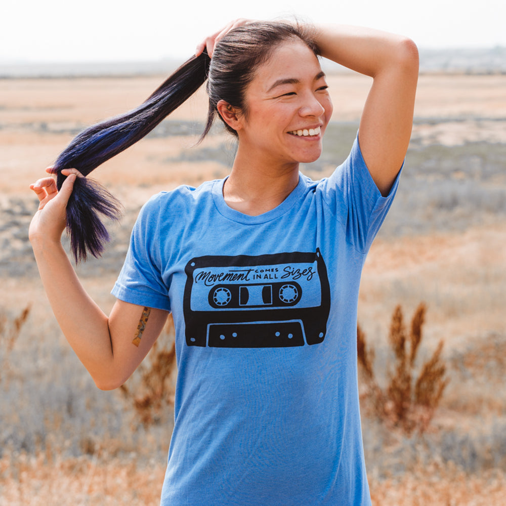 Woman wearing a heather columbia blue t-shirt that says "movement comes in all sizes"