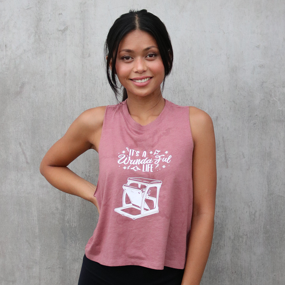 Woman wearing a mauve crop top that says "It's A Wundaful Life" with a wundachair in white text