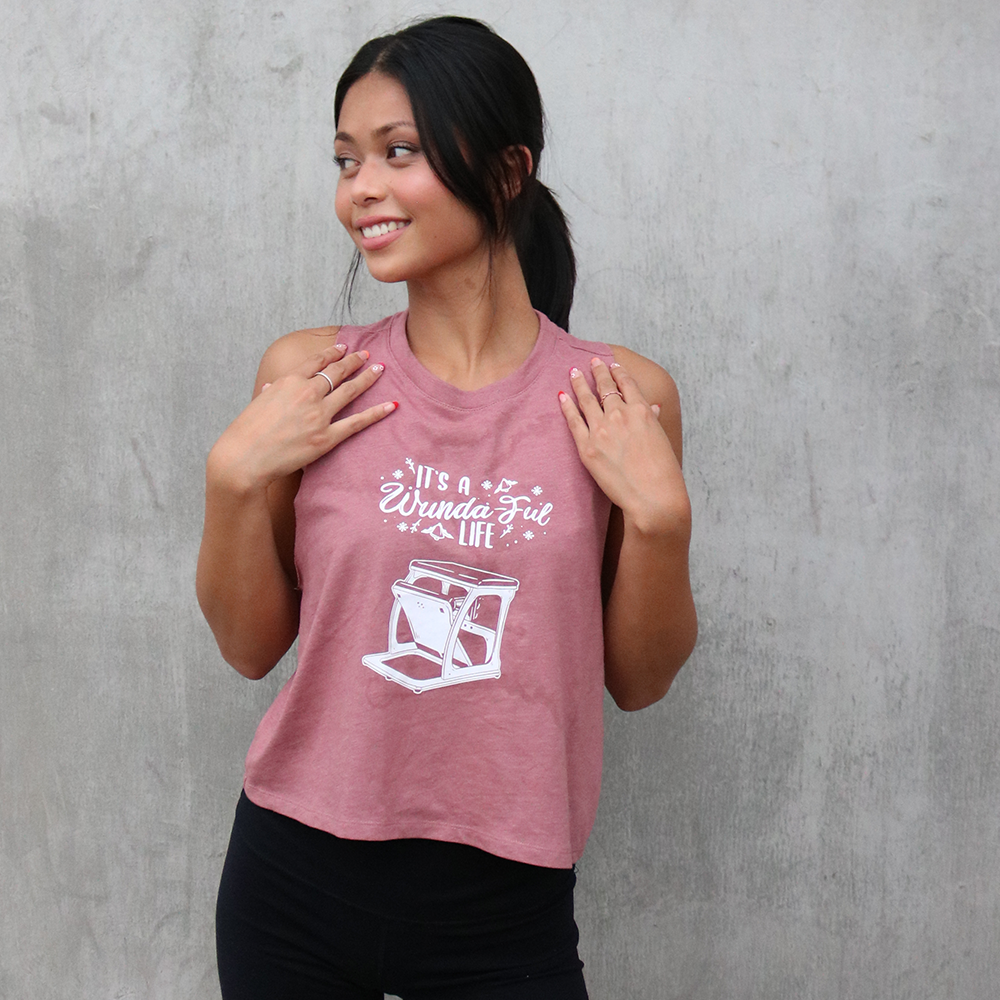 Woman wearing a mauve crop top that says "It's A Wundaful Life" with a wundachair in white text