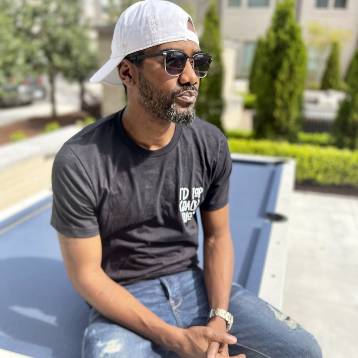 Man wearing a unisex heather black shirt from The Movement Shop that says "I'd Tap (Back) That"