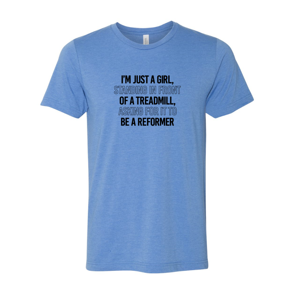Woman wearing a heather columbia blue crewneck t-shirt that says "I'm just a girl standing in from of a treadmill, asking for it to be a reformer"
