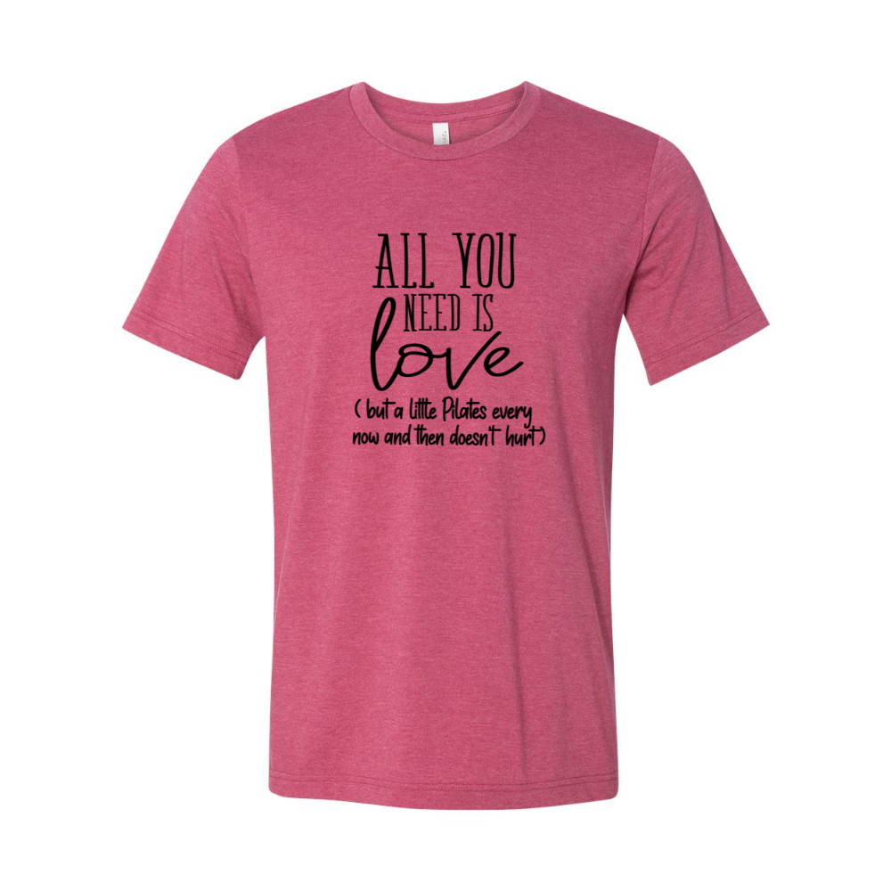 A Heather Raspberry unisex crewneck t-shirt that says "all you need is love" but a little Pilates every now and then doesn't hurt"