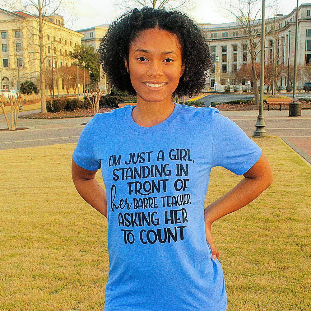 Blue Unisex T-Shirt that says "I'm just a girl, standing in front of her barre teaacher, asking her to count" worn by a woman