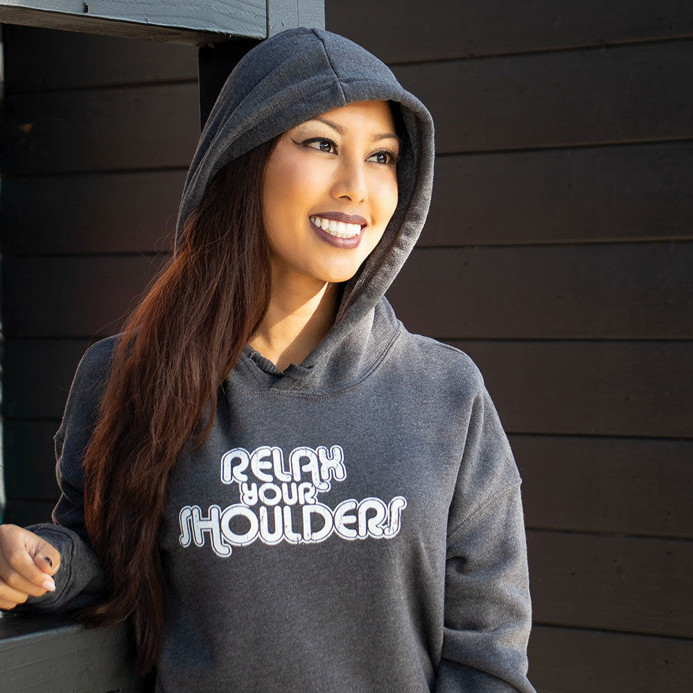 woman wearing a crop hoodie that says "relax your shoulders" in white text