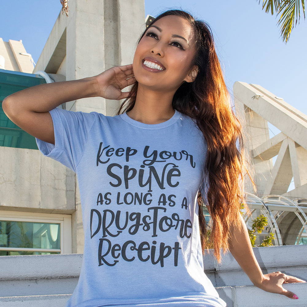 Woman wearing a light blue unisex crew neck t-shirt that says "Keep your spine as long as a drug store receipt"