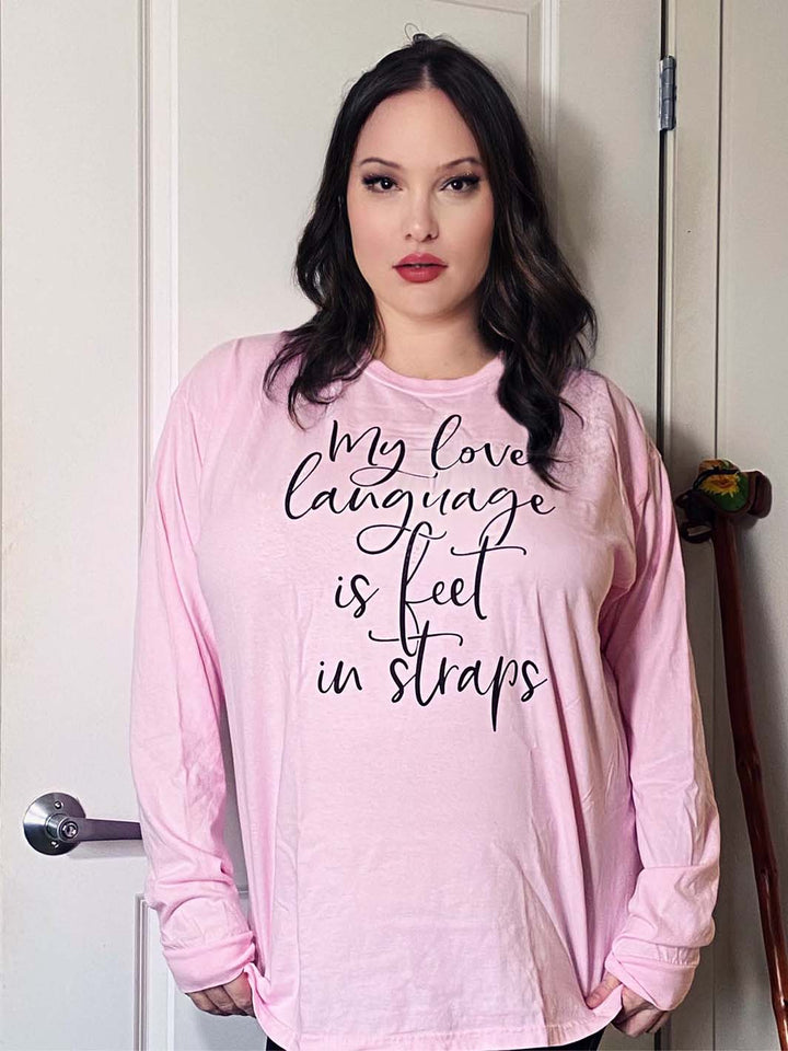 Woman wearing a unisex crew neck long sleeved shirt that says "My Love Language Is Feet In Straps" in black script