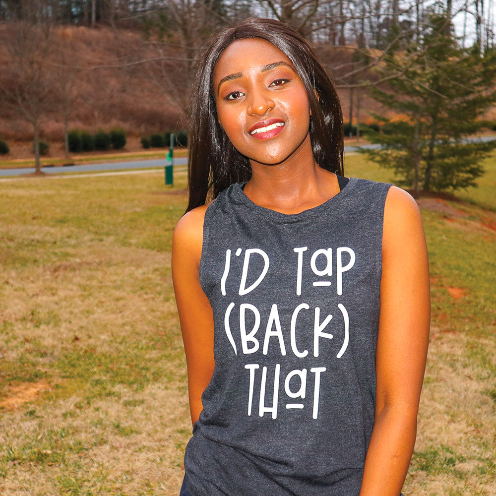 Woman wearing a black muscle tank that says '" I'd Tap (Back) That" in white text