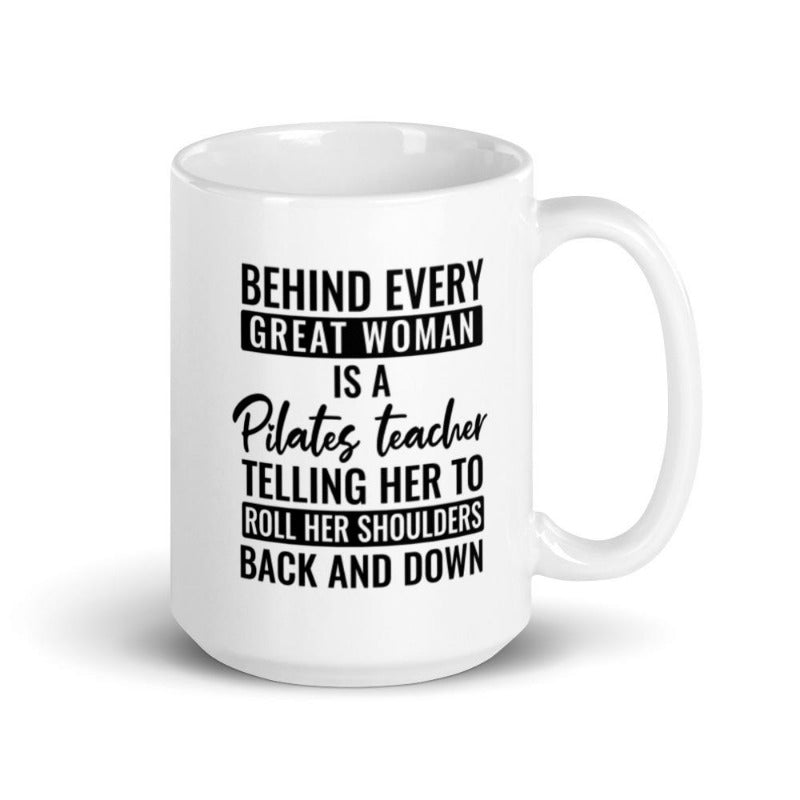 15 oz coffee mug that says "Behind Every Great Woman is A Pilates Teacher telling her to roll her shoulders back and down"