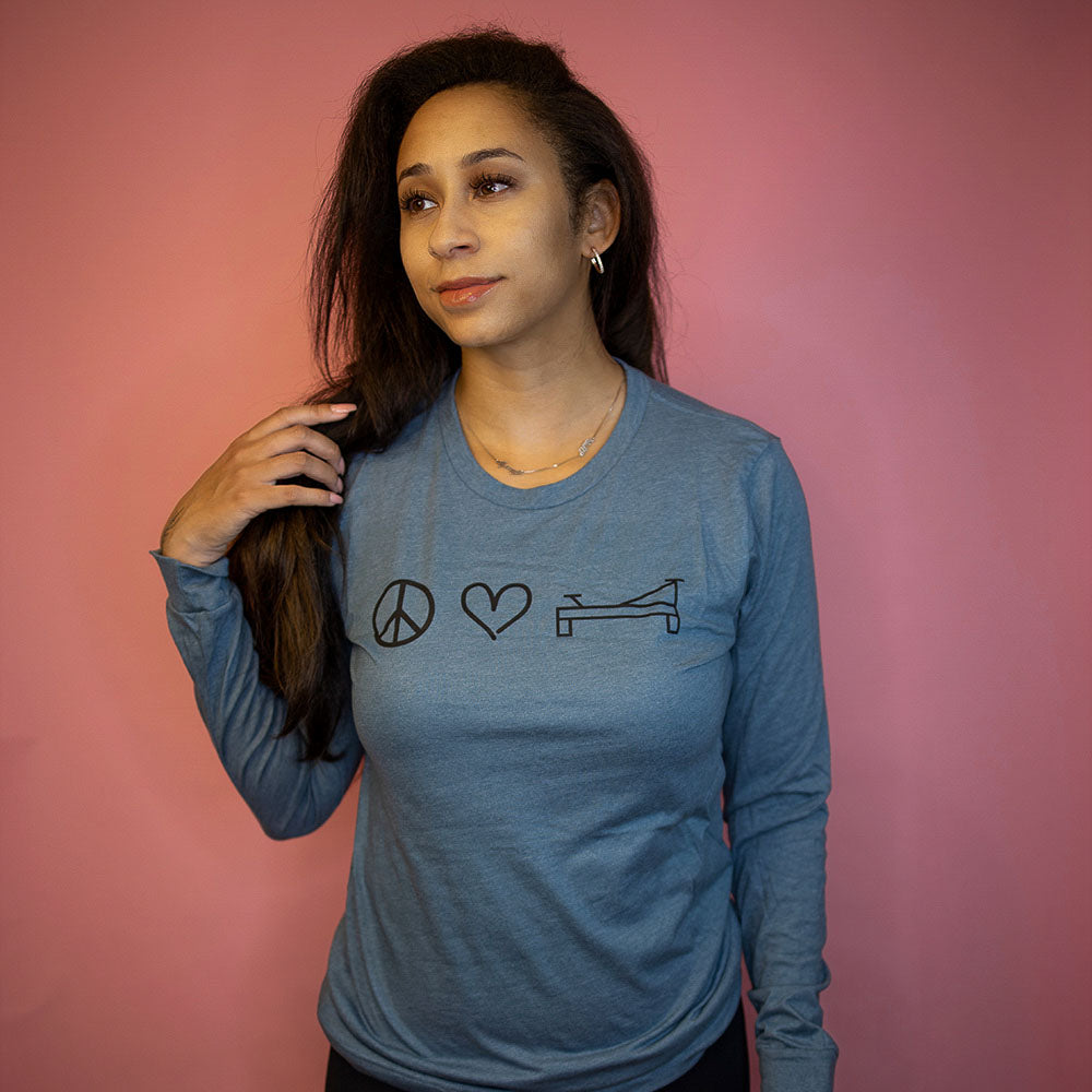 Woman wearing a unisex long sleeve t-shirt that says Peace Love Pilates 