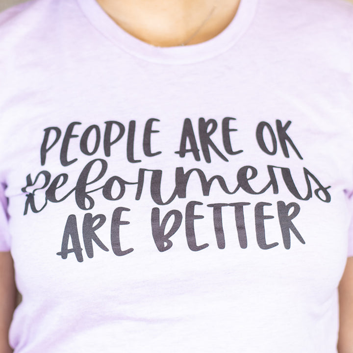 A heather lilac unisex crewneck t-shirt shirt that says "People Are Ok, Reformers Are Better" in black text