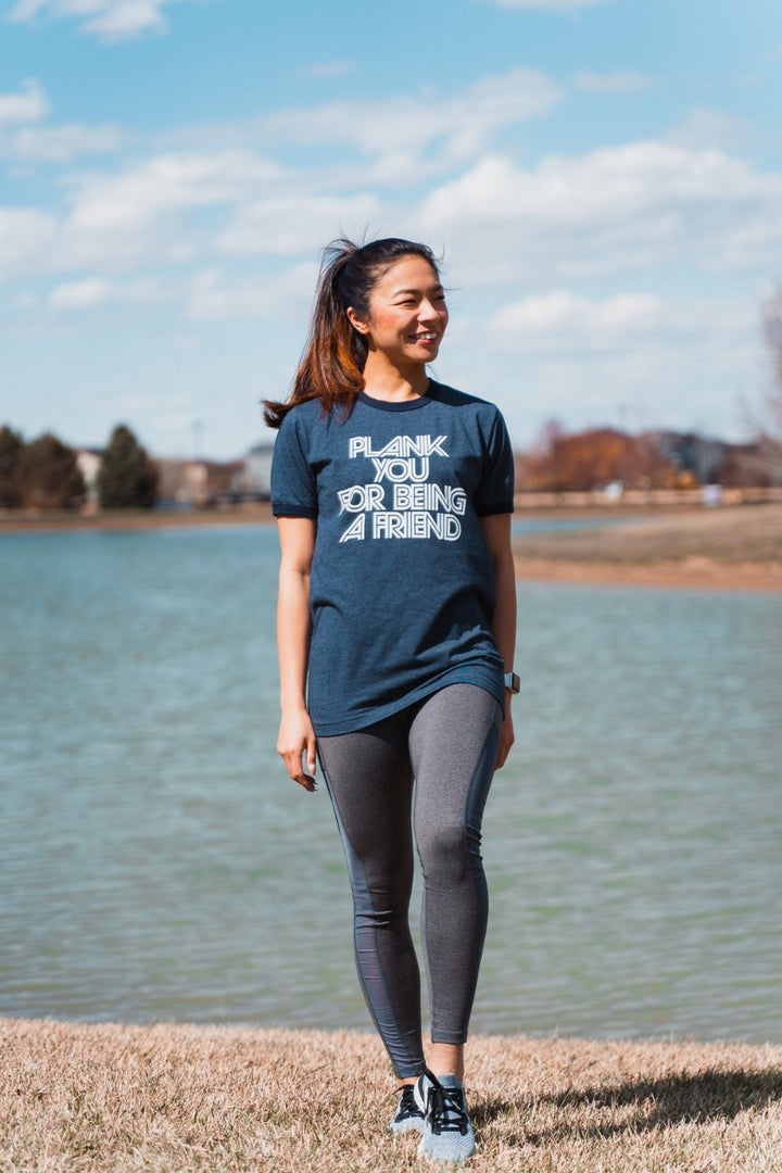 Woman wearing a blue ringer t-shirt that says "plank you for being a friend" in white writing