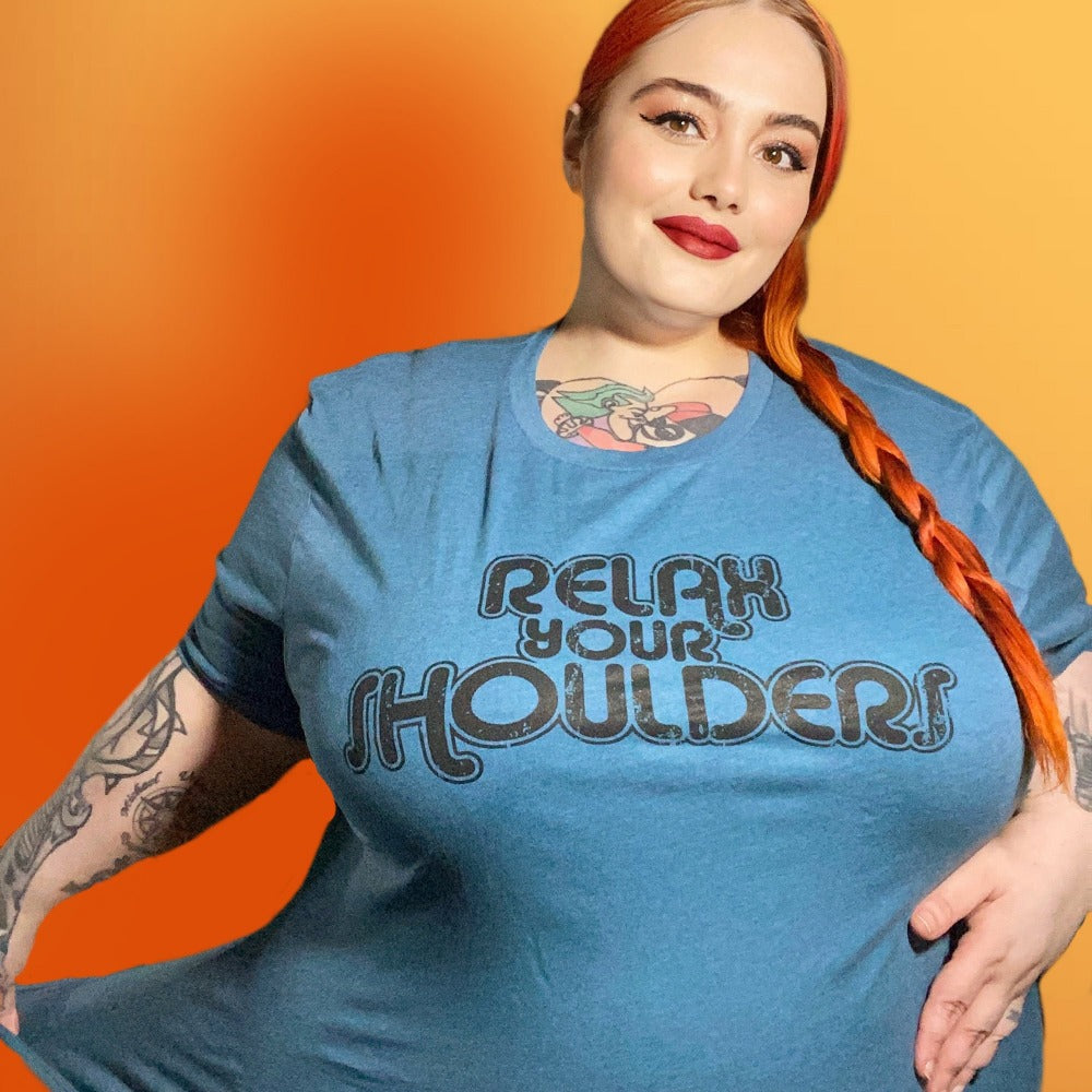 Woman wearing a heather dark teal crewneck t-shirt that says "Relax Your Shoulders" in vintage retro text