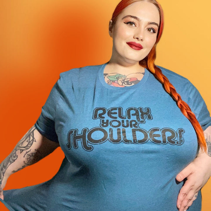 Woman wearing a heather dark teal crewneck t-shirt that says "Relax Your Shoulders" in vintage retro text