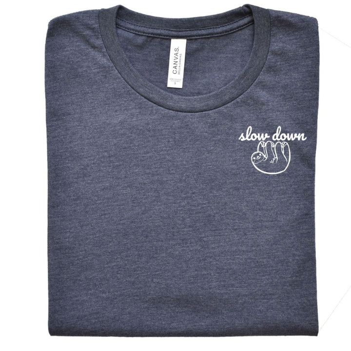Folded Heather Navy Unisex Crewneck T-Shirt that has the text "slow down" in white script over a white sloth on her left chest logo. 