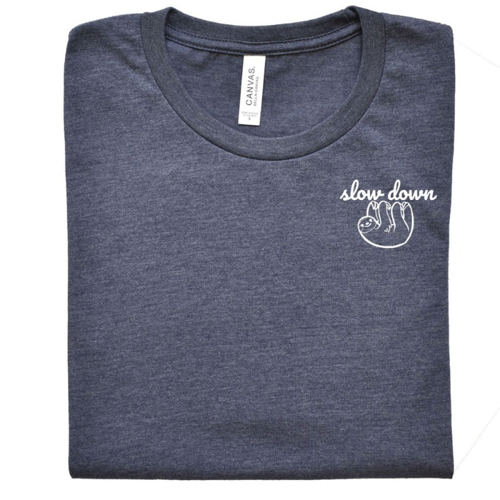 Folded Heather Navy Unisex Crewneck T-Shirt that has the text "slow down" in white script over a white sloth on her left chest logo.