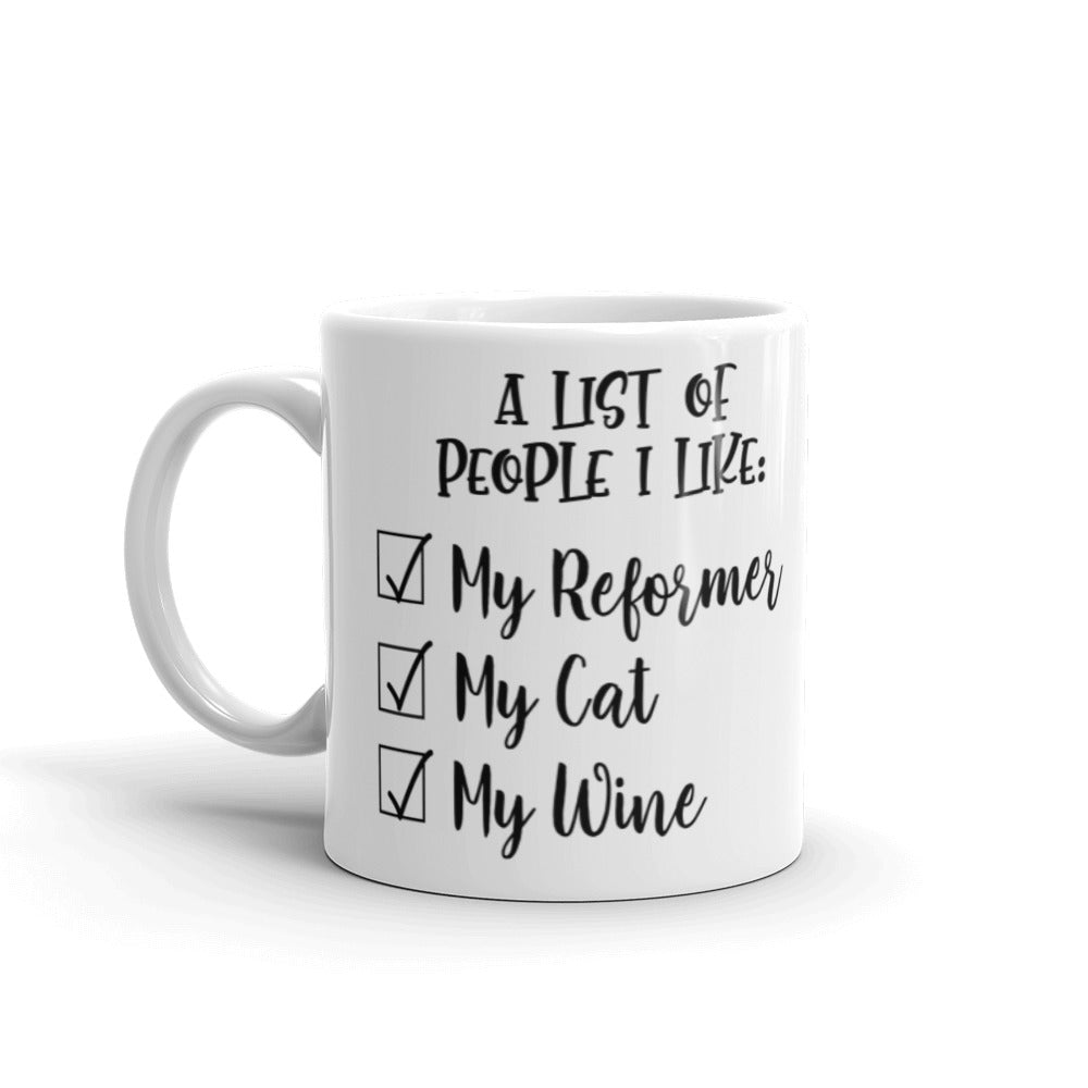 11 oz white coffee mug that says "A list of people I like: My reformer, My Cat, My Wine".