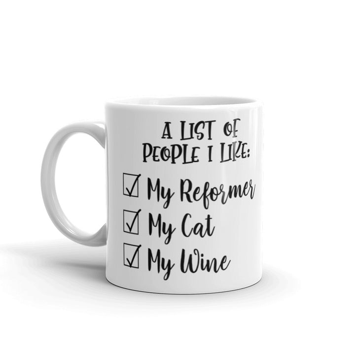 11 oz white coffee mug that says "A list of people I like: My reformer, My Cat, My Wine".