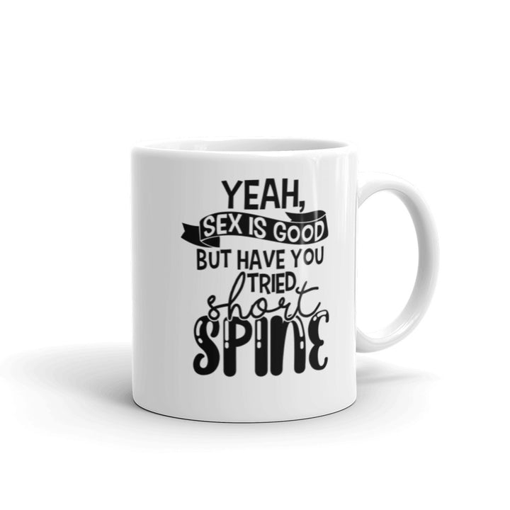 11 oz white coffee mug with handle on the right side. On the mug says " yeah, sex is good but have you tried short spine". Background is white.