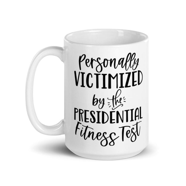 15 oz white ceramic mug that says "Personally victimized by the presidential fitness test"