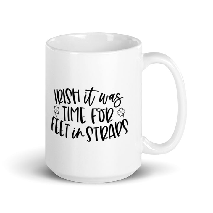 15 oz white coffee mug that says "Irish It Was Time For Feet In Straps" in black text. There are two black outline of 4 leaf clover on the front of the mug.