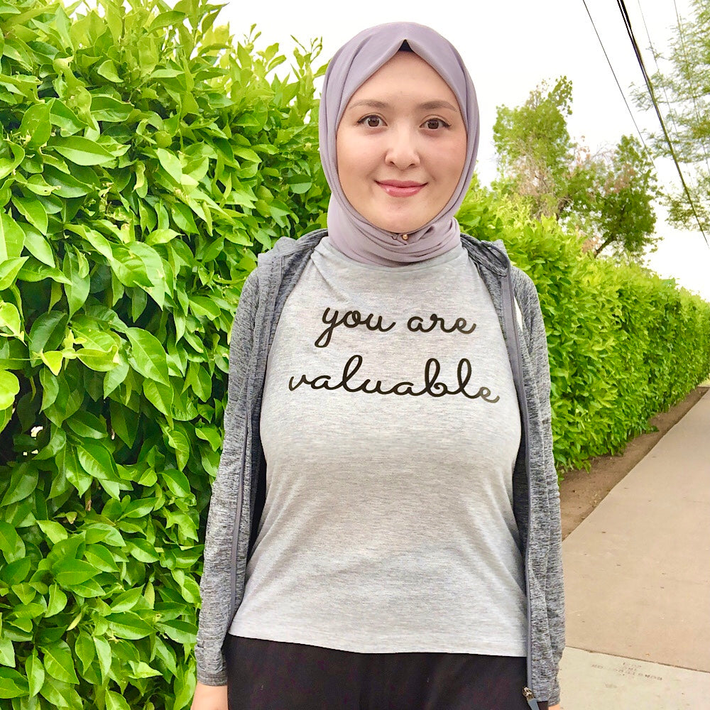 Woman wearing a grey muscle tank top that says "you are valuable"