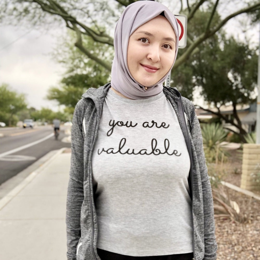 Woman wearing a grey muscle tank top that says "you are valuable"