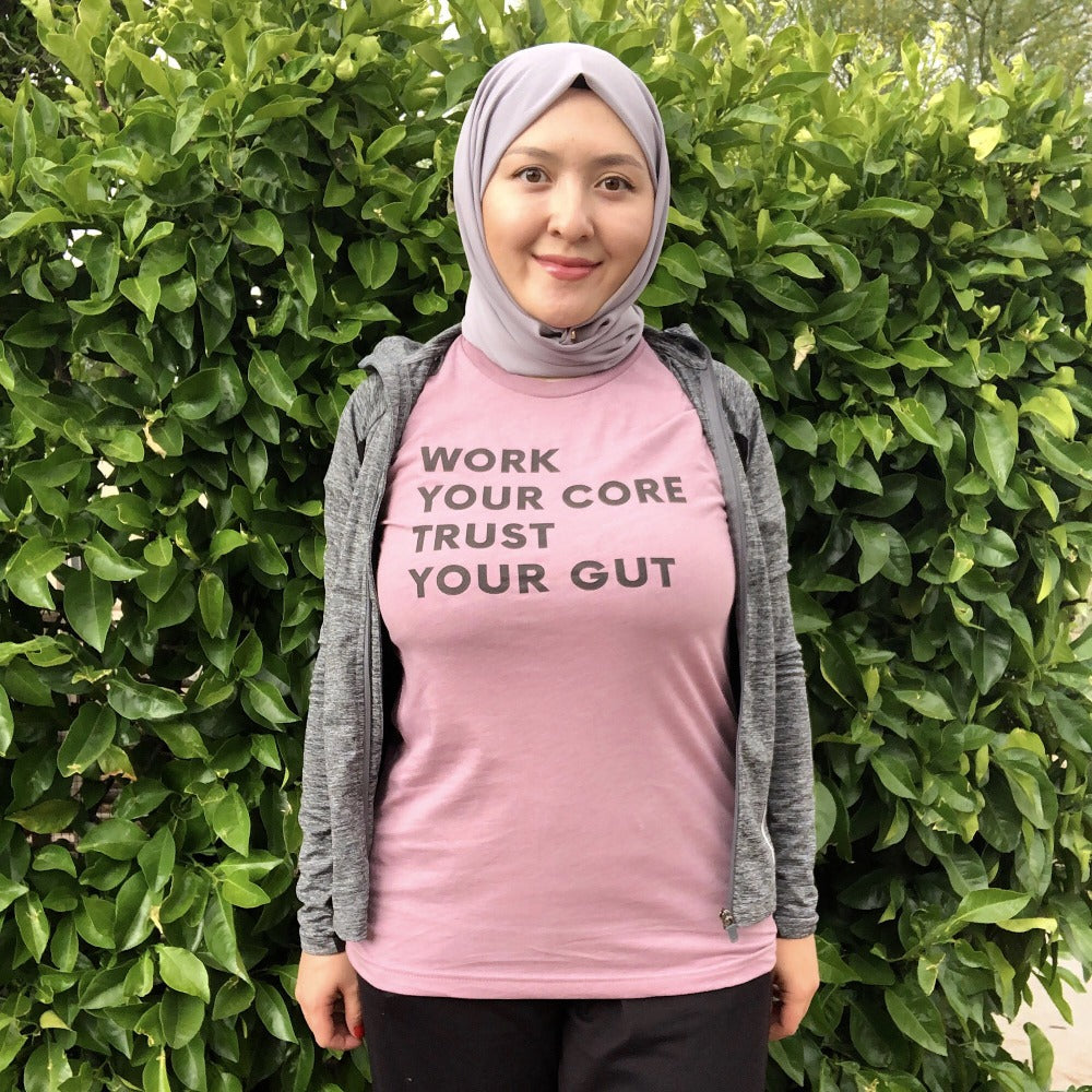 Woman wearing a unisex mauve t-shirt that says "work your core, trust your gut"