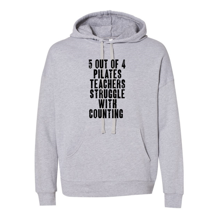 woman wearing a grey unisex hoodie with white drawcord that says "5 out of 4 Pilates Teachers Struggle With Counting"