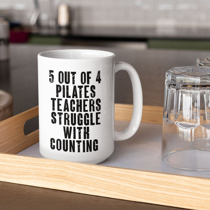 White 15 oz. Coffee Mug that says "5 out of 4 Pilates Teachers Struggle In Counting" in black text