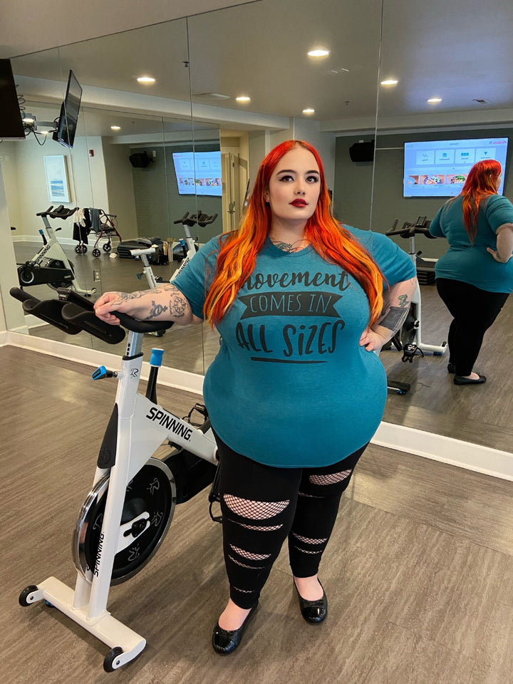 woman wearing Deap Heather Teal t-shirt that says "Movement Comes IN All Sizes"