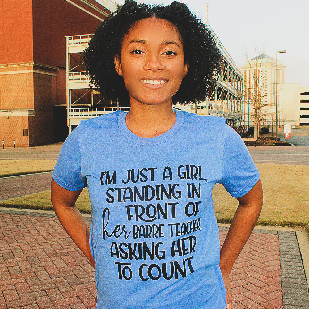 Blue Unisex T-Shirt that says "I'm just a girl, standing in front of her barre teaacher, asking her to count" worn by a woman