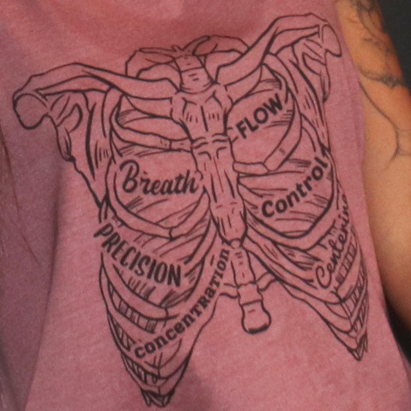 Woman wearing a mauve crop tank top that has a hand drawn rib cage on the front of the tank. The 6 Pilates Principles (flow, control, concentration, precision, breath) are incorporated into the rib design