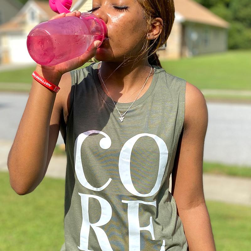 Woman wearing an olive woman's cut muscle tank top that says CORE in white letters