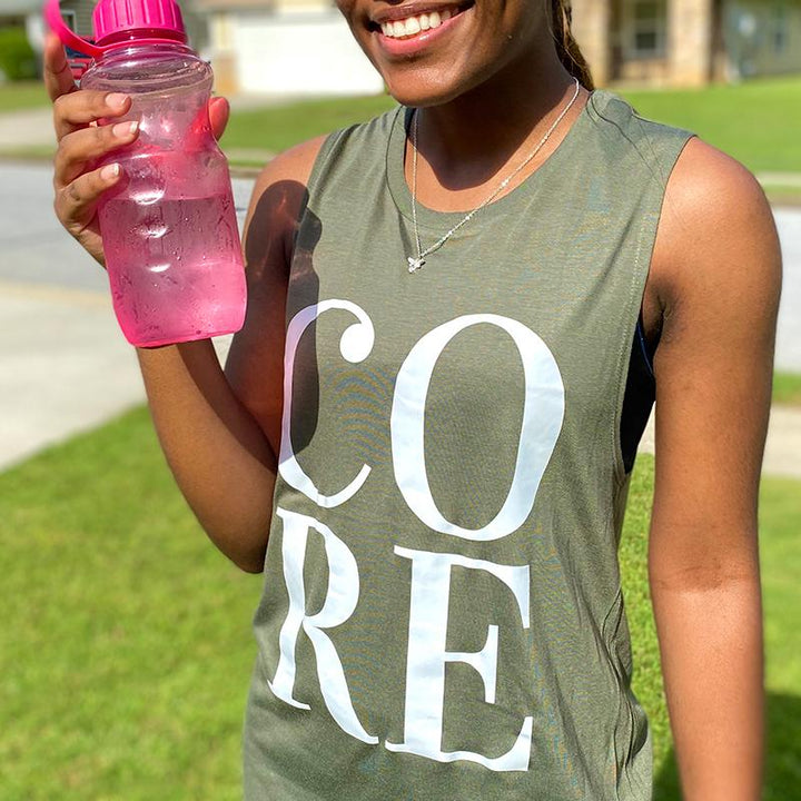 Woman wearing an olive woman's cut muscle tank top that says CORE in white letters