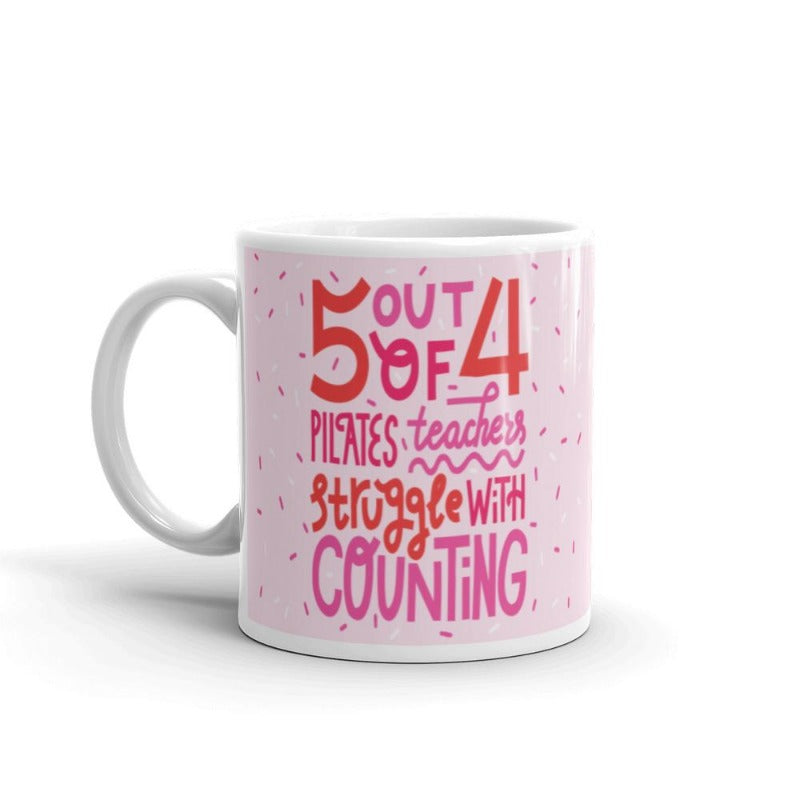 11 oz white coffee mug that says 5 out 4 Pilates Teachers struggle with counting. Mug has a white base and text is pink and white with the design.