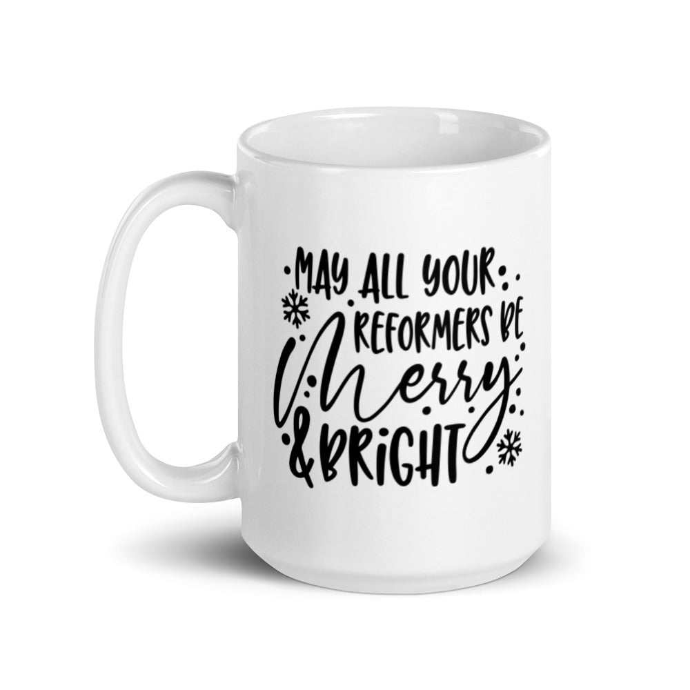 15oz white coffee mug that says "May All Your Reformers Be Merry and Bright" in Christmas style black text. 