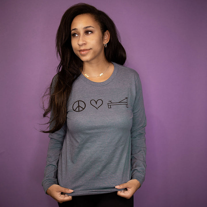Woman wearing a unisex long sleeve t-shirt that says Peace Love Pilates 