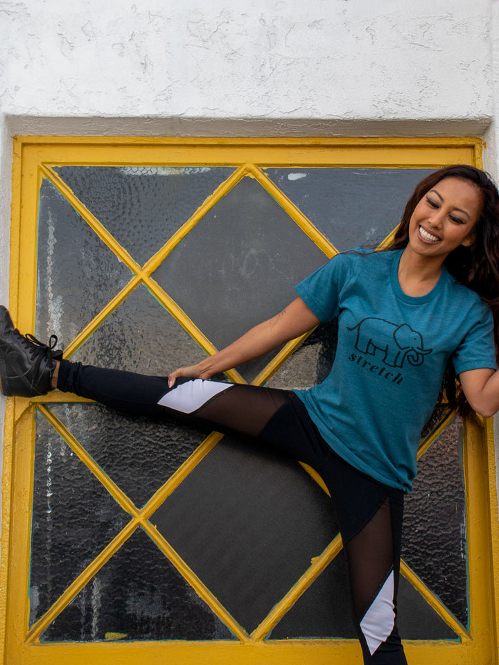 Woman wearing a unisex crewneck deep heather teal shirt that has an elephant in a black outline and the words stretch in bkack cursive text 