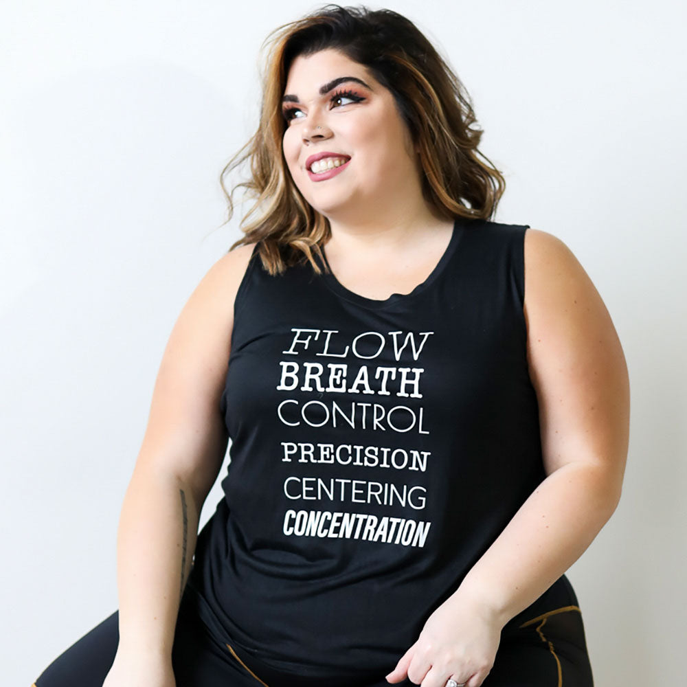 Woman wearing a black muscle tank top that says "Flow, Breath, Control, Precision, Centering, and Concentration" in various fonts. Text is white