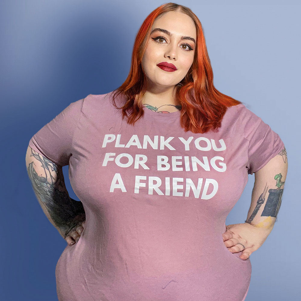 Woman wearing a heather orchid unisex crewneck t-shirt that says "Plank You For Being A Friend" in white text