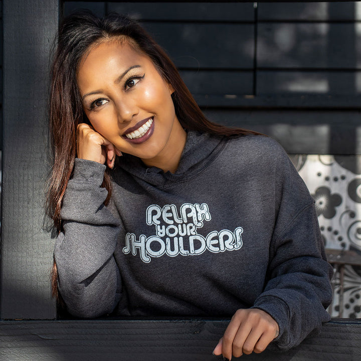 woman wearing a crop hoodie that says "relax your shoulders" in white text