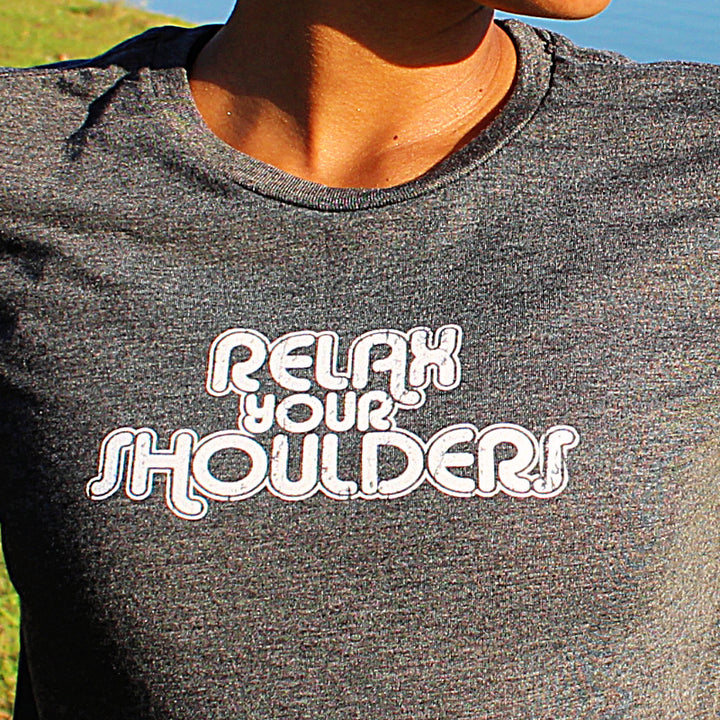 Woman wearing a heather gray cropped t-shirt that says "relax your shoulders"