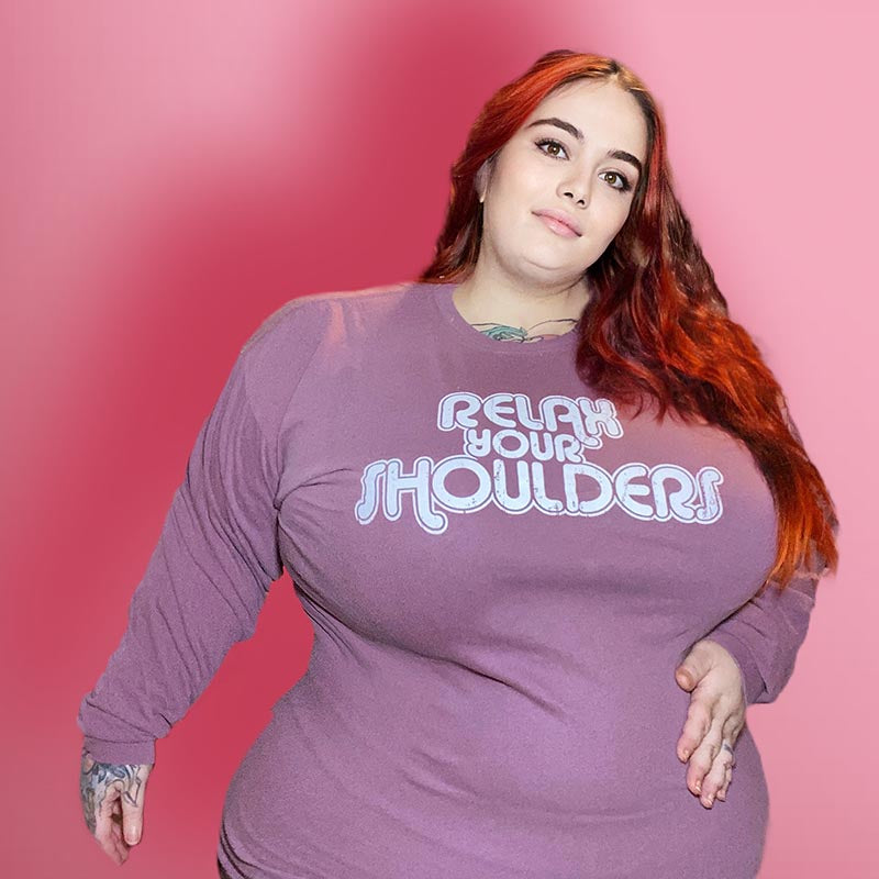 Woman wearing a long sleeve maroon shirt that says "relax your shoulders" in retro font