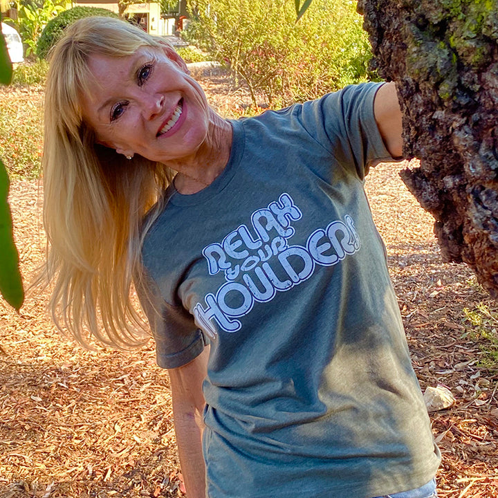 Woman wearing a heather military green shirt that says "relax your shoulders" in white retro text