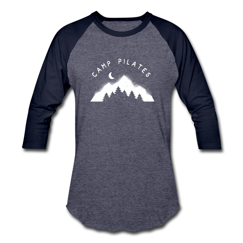 Woman wearing a 3/4 sleeve baseball shirt that says "Camp Pilates" over a mountain design. Both the text and design is in white. 