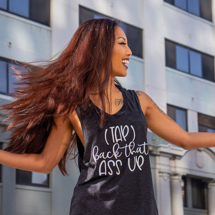 woman wearing a black muscle tank top that says "(Tap) Back that Ass Up"