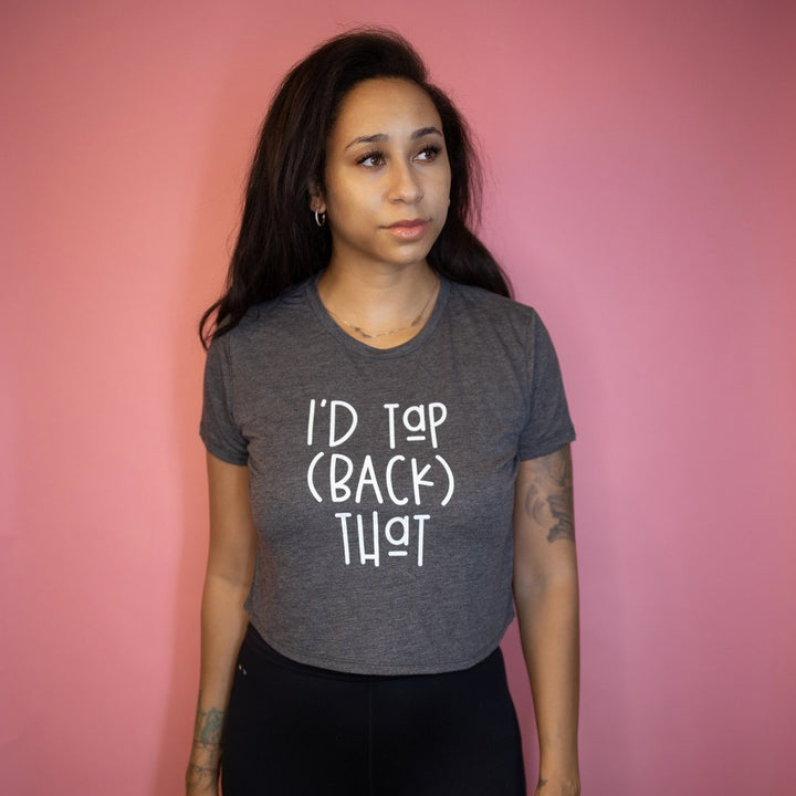 Woman wearing a dark grey women's cut cropped t-shirt that says "I'd Tap (Back) That" in white text